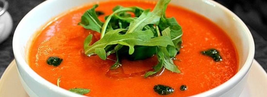 Kürbissuppe in einer Schale angerichtet, mit Salatblättern garniert