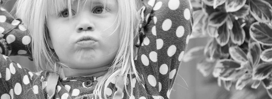 Ein Mädchen verschränkt die Arme hinter dem Kopf und schaut schmollend.