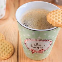 Kaffeebecher mit dem Aufdruck "be happy" und Keksen