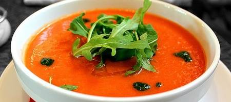 Kürbissuppe in einer Schale angerichtet, mit Salatblättern garniert