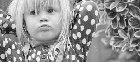 Ein Mädchen verschränkt die Arme hinter dem Kopf und schaut schmollend.