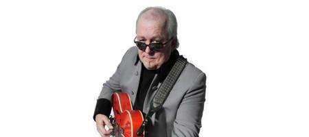 Ein Mann mit Sonnenbrille spielt auf einer Gitarre.