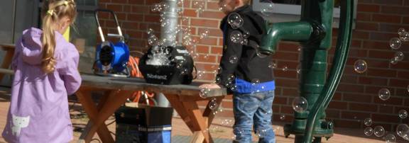 Zwei Kinder bestaunen die Seifenblasen