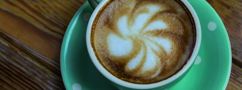 Kaffee in einer gepunkteten Tasse mit dekorativem Schaum